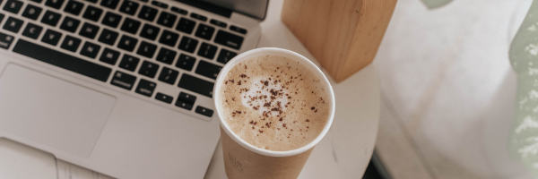 Start A Freelance Writing Career - Image shows a laptop and paper cup of coffee sitting on a small circular table