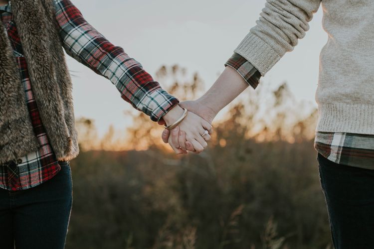 Two people holding hands in field