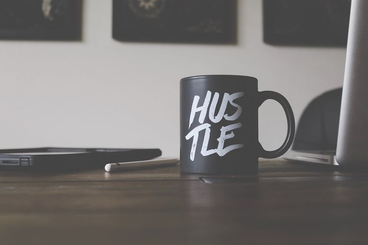 Mug with 'hustle' text on desk