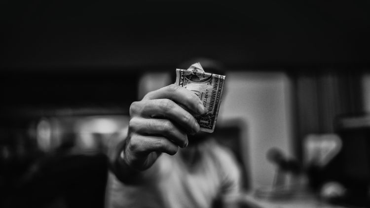 Person holding bank note towards the camera.